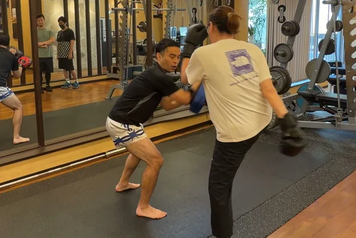トレーナーが構えるミットにひざ蹴りを入れる参加者
